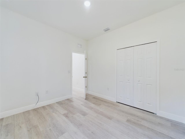 unfurnished bedroom featuring baseboards, a closet, light wood-style flooring, and visible vents