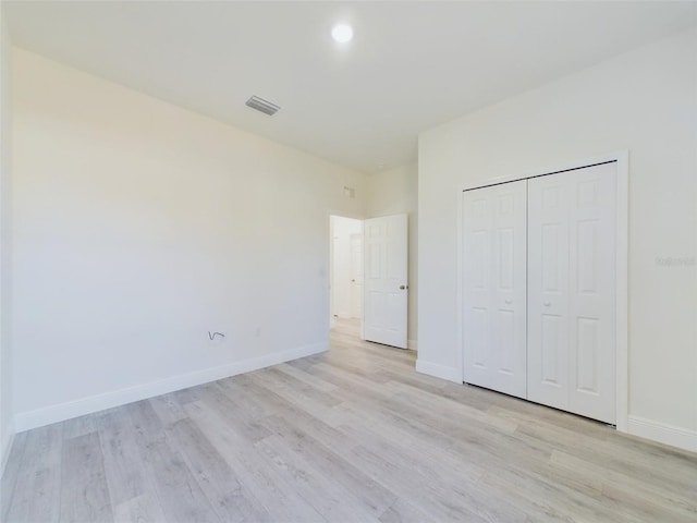 unfurnished bedroom with light wood-type flooring, baseboards, a closet, and visible vents