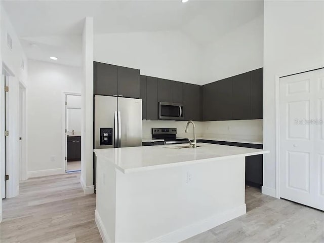 4415 SW 169th Lane Rd, Ocala, FL 34473 - kitchen featuring stainless steel appliances, dark cabinetry, high vaulted ceiling, a center island with sink, and light countertops