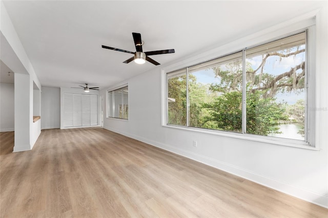 unfurnished living room with light wood finished floors, baseboards, and ceiling fan