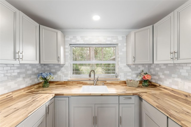 kitchen with wood counters, tasteful backsplash, and a sink