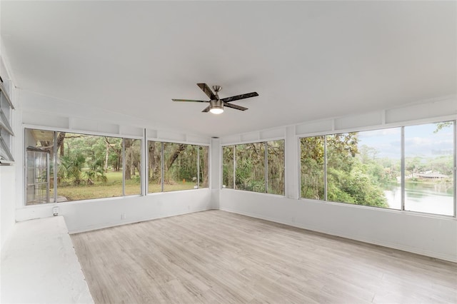 unfurnished sunroom featuring ceiling fan, a water view, baseboards, and wood finished floors