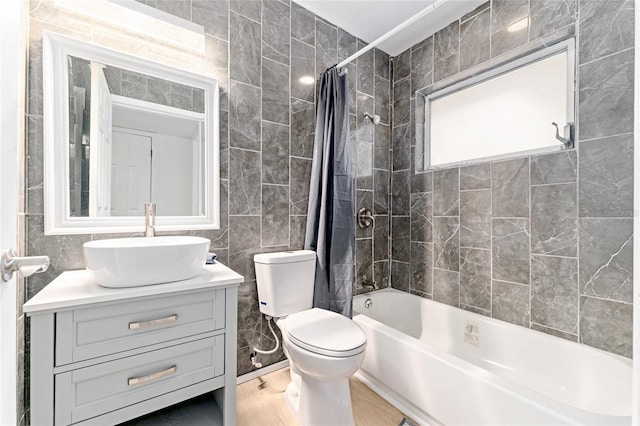 full bath featuring tile walls, toilet, wood finished floors, vanity, and shower / bath combo