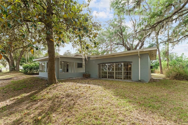 back of property featuring a lawn and stucco siding