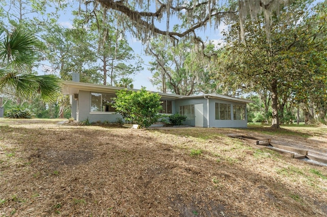 view of front facade featuring stucco siding and a chimney