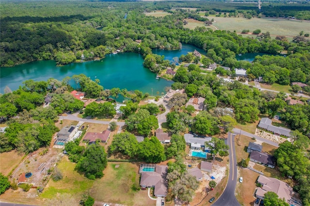 birds eye view of property with a water view and a wooded view