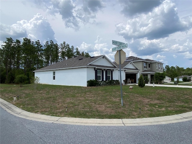 view of front facade featuring stucco siding, a front yard, a garage, and driveway