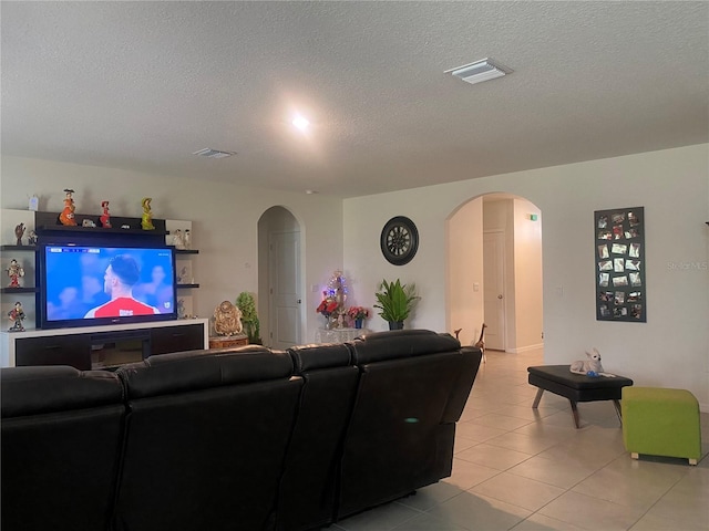 living area featuring arched walkways, a textured ceiling, and light tile patterned floors