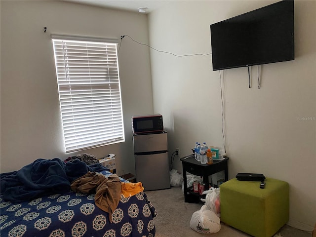 carpeted bedroom with freestanding refrigerator