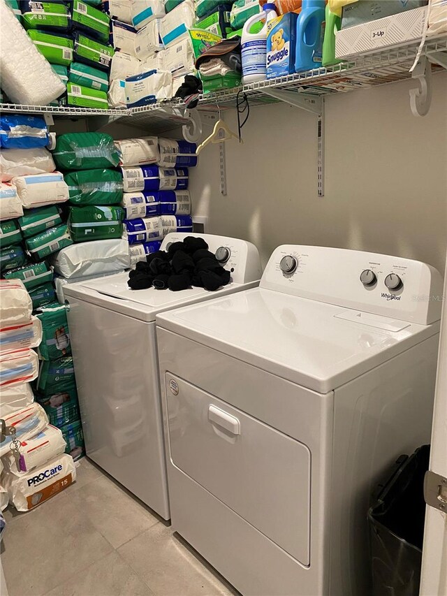 laundry area with washer and clothes dryer and light tile patterned floors