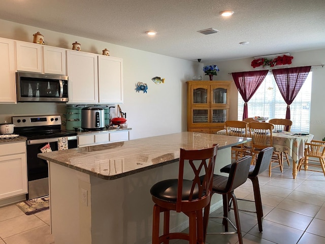12 Hickory Course Way, Ocala, FL 34472 - kitchen featuring appliances with stainless steel finishes, a breakfast bar area, light stone countertops, a kitchen island, and light tile patterned floors