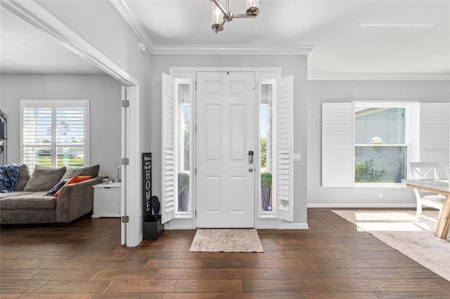entryway with dark wood-type flooring, ornamental molding, a chandelier, and baseboards