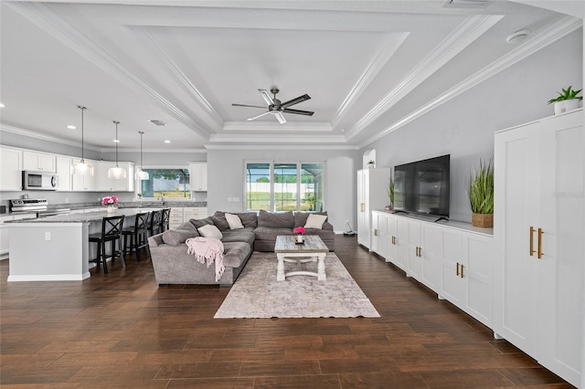 living room with a tray ceiling, dark wood finished floors, crown molding, a ceiling fan, and recessed lighting