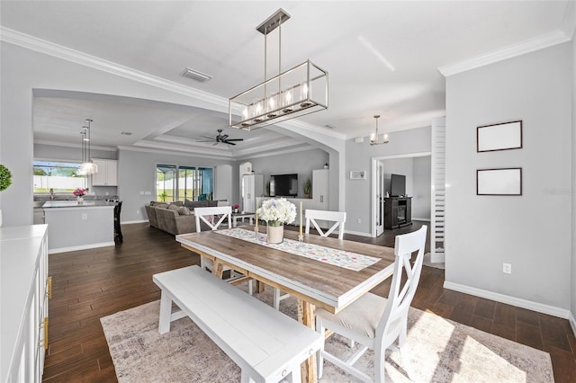 dining room featuring a ceiling fan, crown molding, dark wood-style flooring, baseboards, and a chandelier