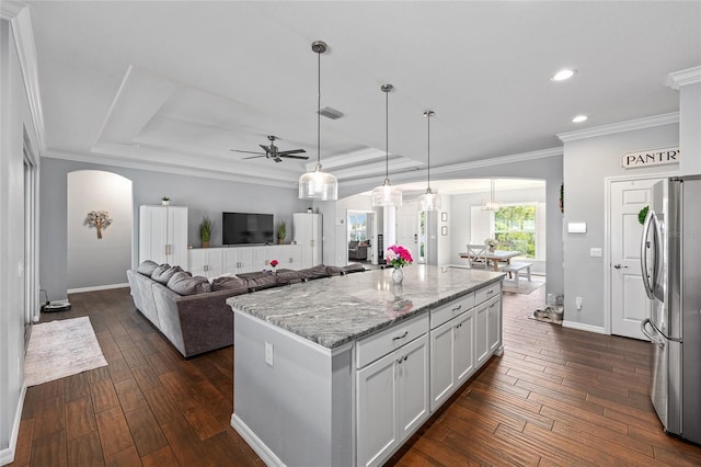 kitchen with freestanding refrigerator, arched walkways, dark wood-type flooring, ceiling fan, and a tray ceiling