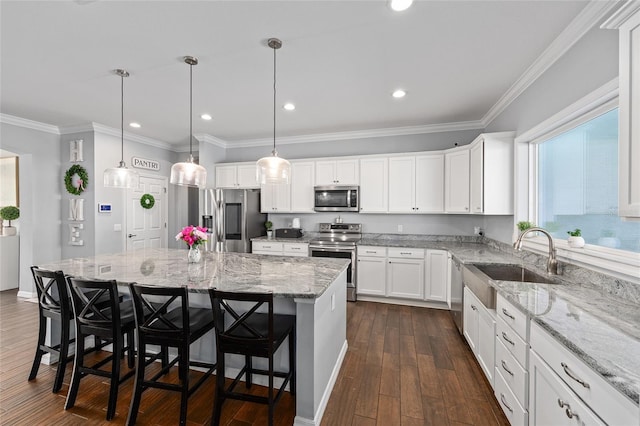 kitchen with appliances with stainless steel finishes, a sink, dark wood finished floors, a kitchen island, and white cabinets