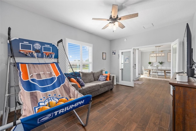 living room with dark wood-type flooring, a ceiling fan, baseboards, and a chandelier