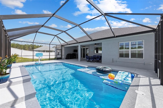 view of pool with a patio, ceiling fan, glass enclosure, and fence