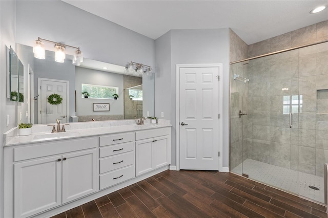 bathroom featuring a stall shower, wood finished floors, double vanity, toilet, and recessed lighting
