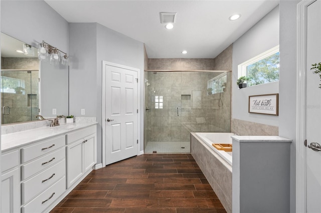 full bathroom with a shower stall, vanity, wood finish floors, a garden tub, and recessed lighting