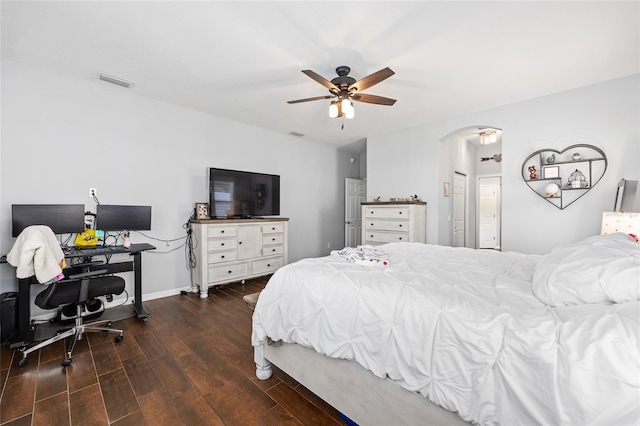 bedroom featuring arched walkways, wood finished floors, ceiling fan, baseboards, and an office area