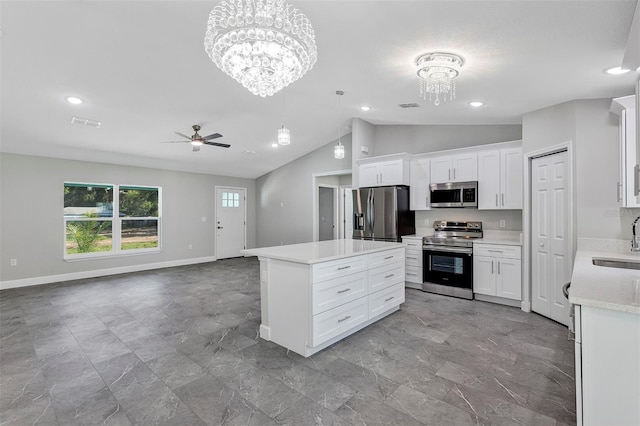 kitchen with ceiling fan with notable chandelier, a sink, stainless steel appliances, light countertops, and vaulted ceiling