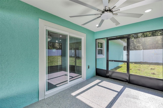 unfurnished sunroom with ceiling fan