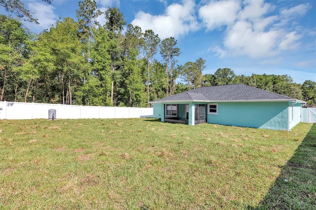 rear view of house with stucco siding, a lawn, and a fenced backyard