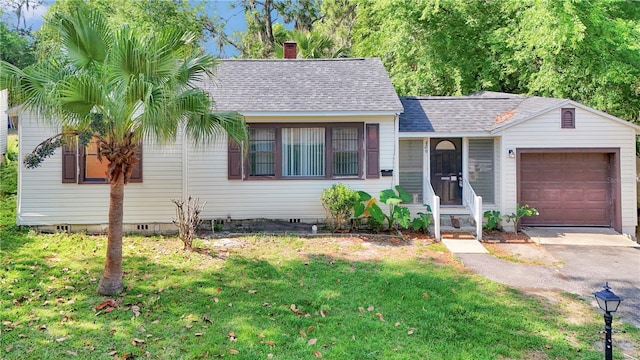 view of front of home with a garage, roof with shingles, a front yard, and a chimney