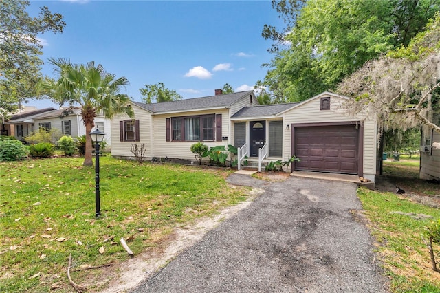 ranch-style home featuring a garage, a front lawn, asphalt driveway, and a chimney