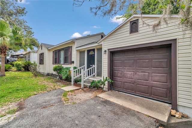 view of front of home featuring driveway, a garage, a front lawn, and entry steps
