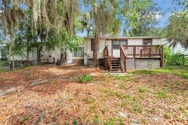 rear view of property with a wooden deck, fence, and stairs