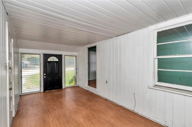 foyer entrance with wood finished floors and wooden walls