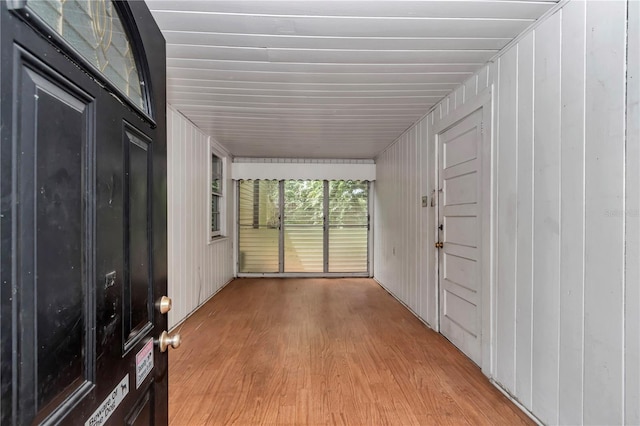hallway featuring light wood finished floors and wooden walls