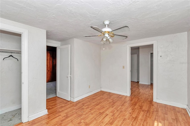 unfurnished bedroom with light wood-style flooring, baseboards, a ceiling fan, a textured ceiling, and a closet