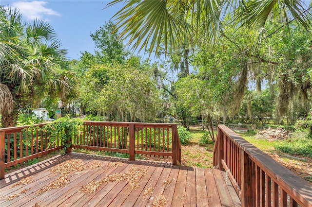 deck featuring fence and view of wooded area