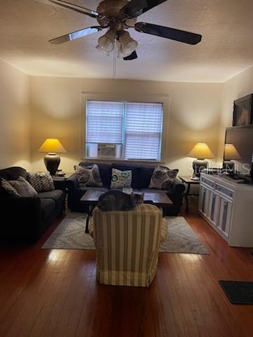 living room with dark wood-style floors and a ceiling fan