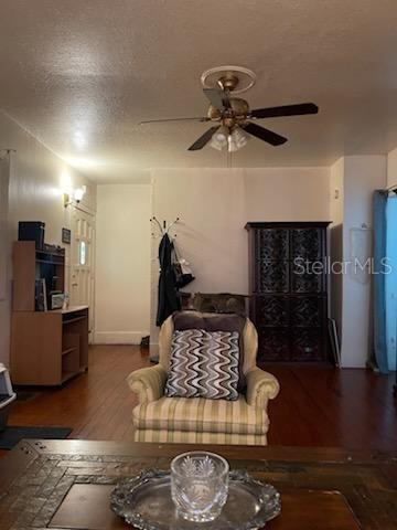 living area featuring wood finished floors, a ceiling fan, and a textured ceiling