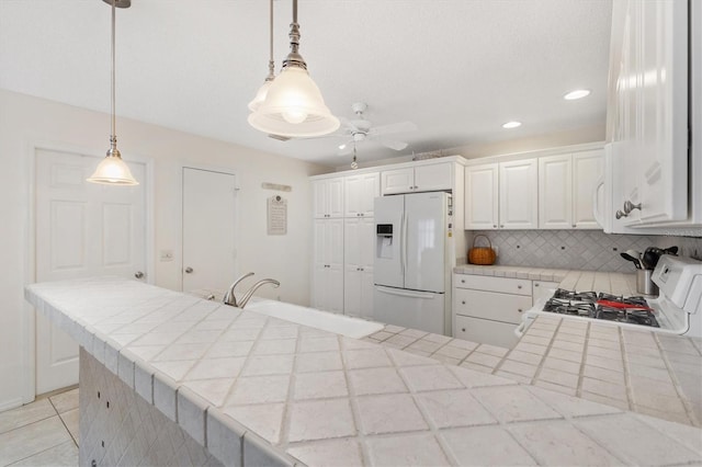 1736 Watts Mill Way, The Villages, FL 32162 - kitchen with white appliances, tile counters, a peninsula, backsplash, and ceiling fan
