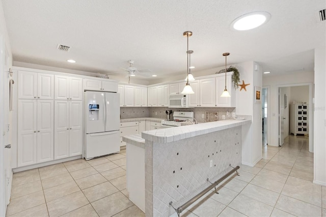 1736 Watts Mill Way, The Villages, FL 32162 - kitchen featuring white appliances, light tile patterned floors, a peninsula, a ceiling fan, and white cabinetry