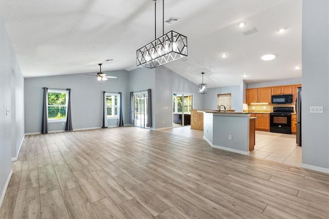 kitchen with black appliances, vaulted ceiling, open floor plan, ceiling fan, and light wood-type flooring