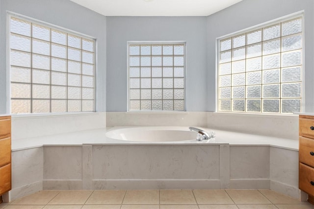 bathroom with healthy amount of natural light, vanity, a garden tub, and tile patterned floors