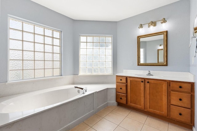 bathroom with healthy amount of natural light, a garden tub, tile patterned flooring, and vanity