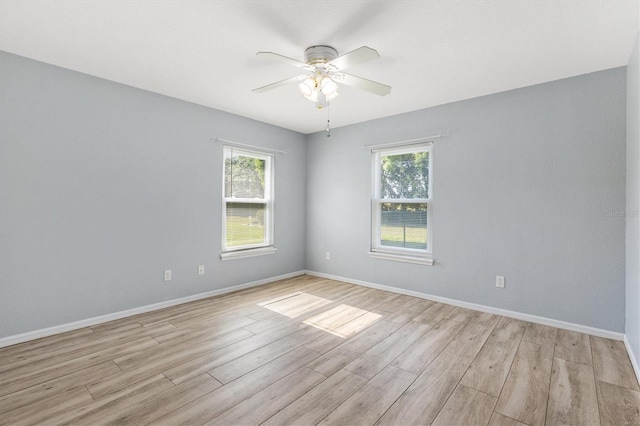spare room with light wood-style flooring, plenty of natural light, ceiling fan, and baseboards