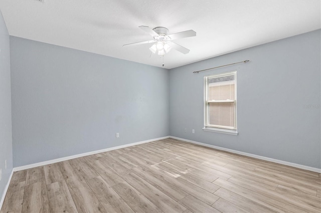 empty room with wood finished floors, a ceiling fan, and baseboards