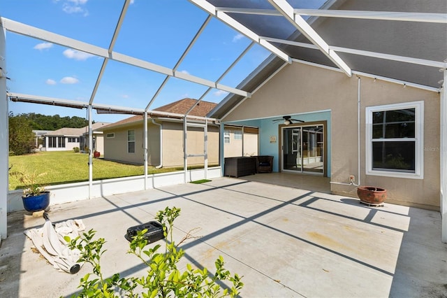 back of property featuring a patio, a ceiling fan, a yard, stucco siding, and glass enclosure