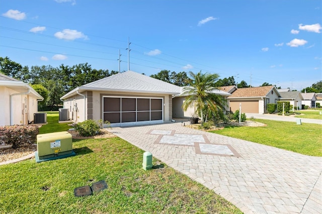 single story home with central AC unit, a front lawn, stucco siding, and decorative driveway