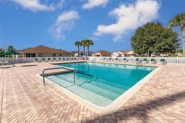 community pool with fence and a patio area