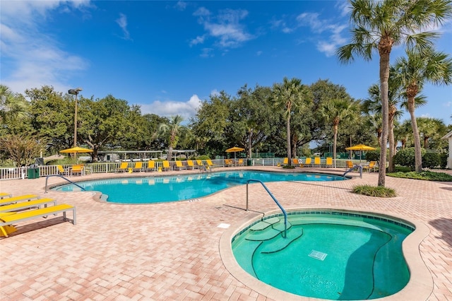 community pool featuring fence, a patio, and view of scattered trees
