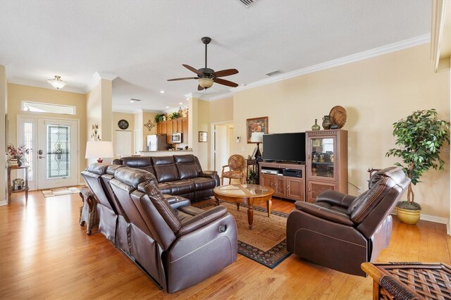 living area with light wood-type flooring, ceiling fan, crown molding, and baseboards